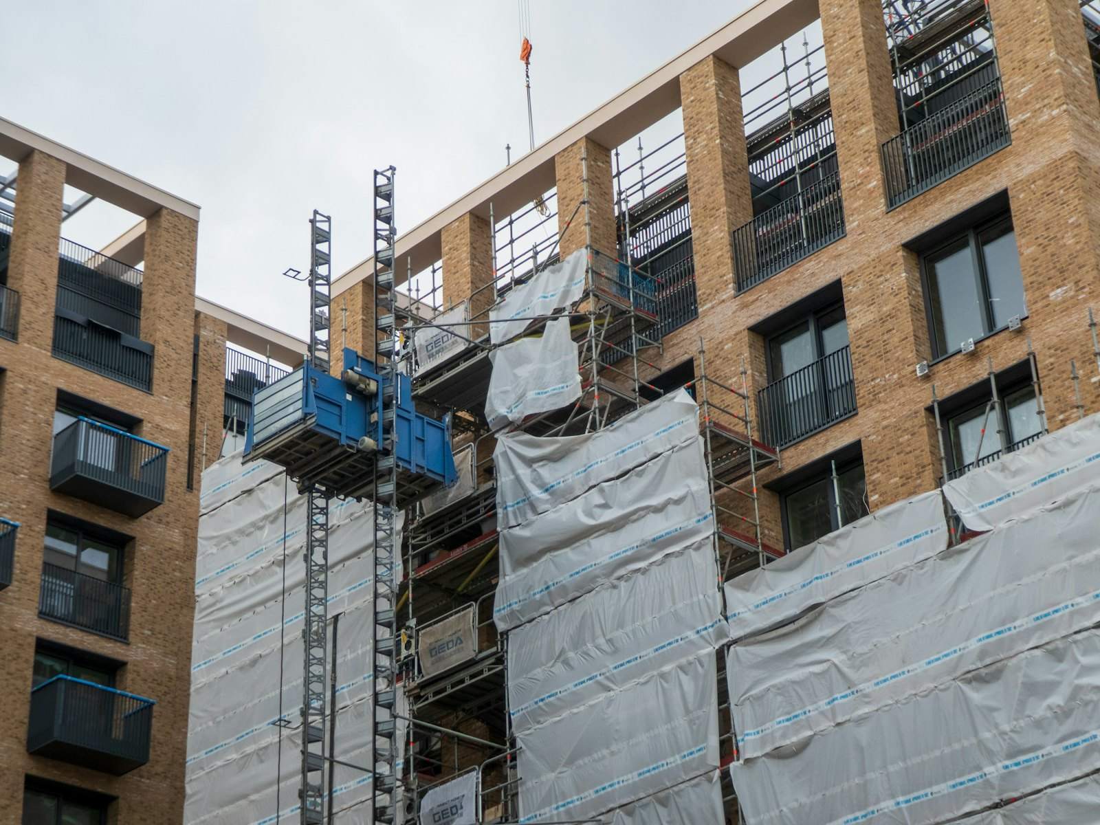Brick apartment building under construction with a hoist