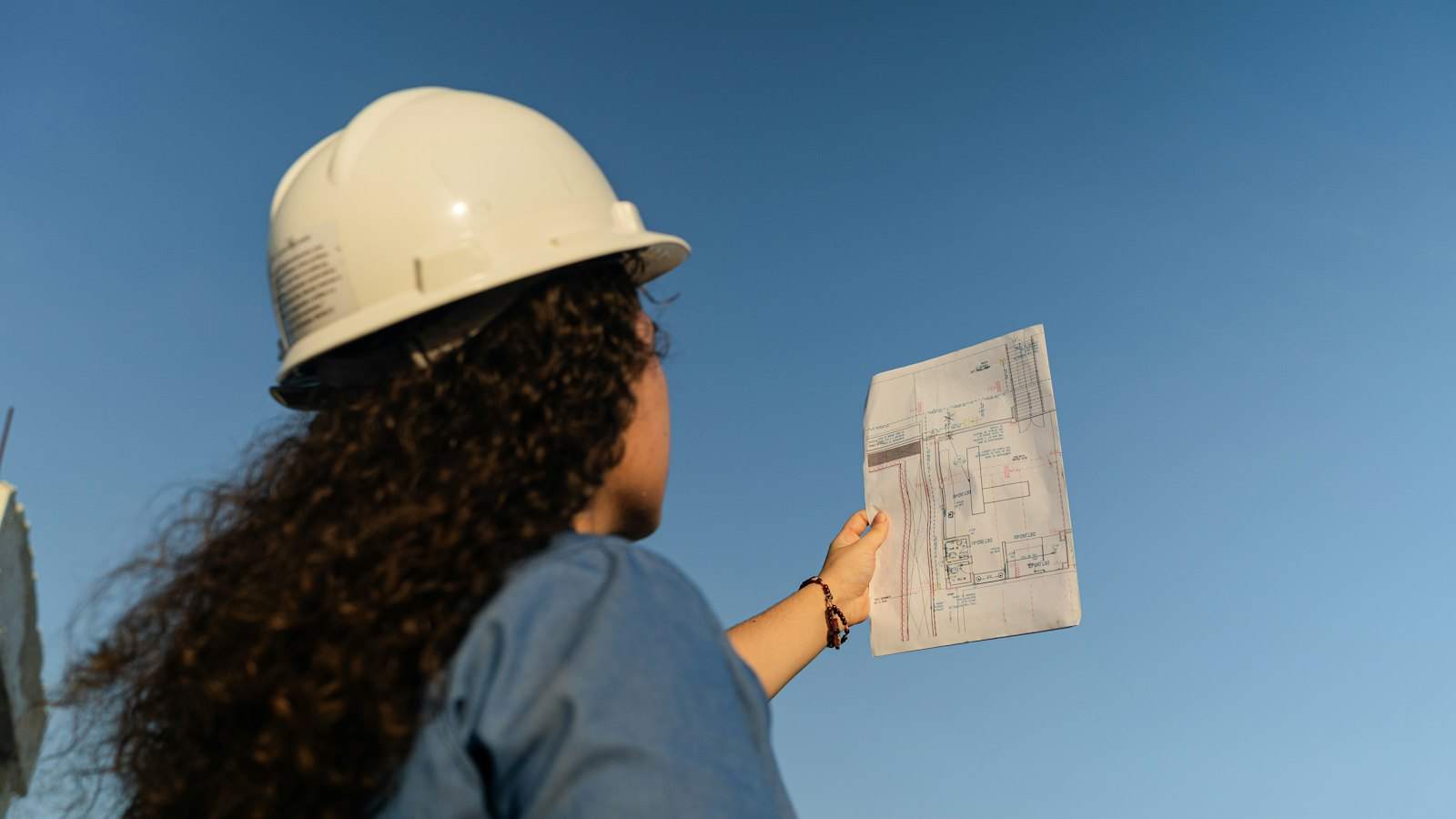 Surveyor in a hard hat checking building plans on site